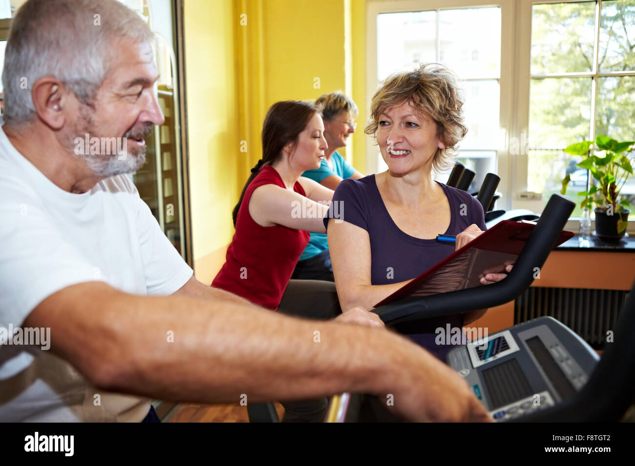 Trainer explaining spinning bike in a gym Stock Photo Alamy