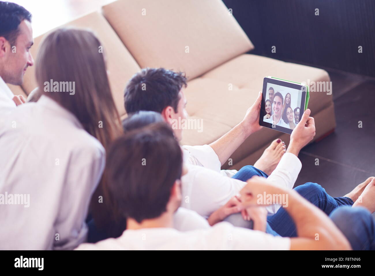 group of friends taking selfie photo with tablet at modern home indoors ...