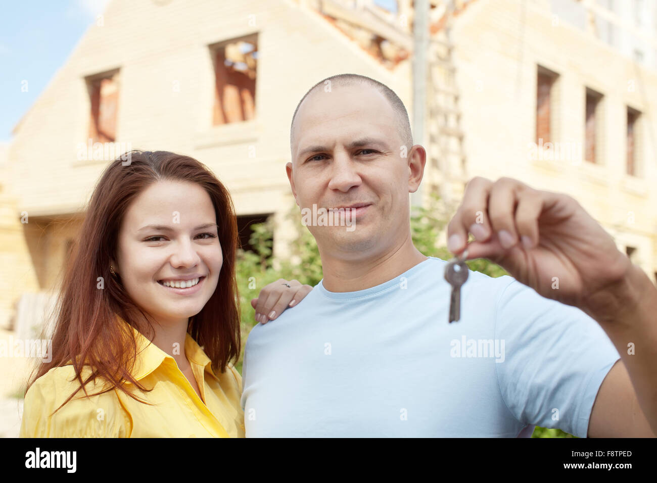 Happy couple with key against building new brick house Stock Photo - Alamy