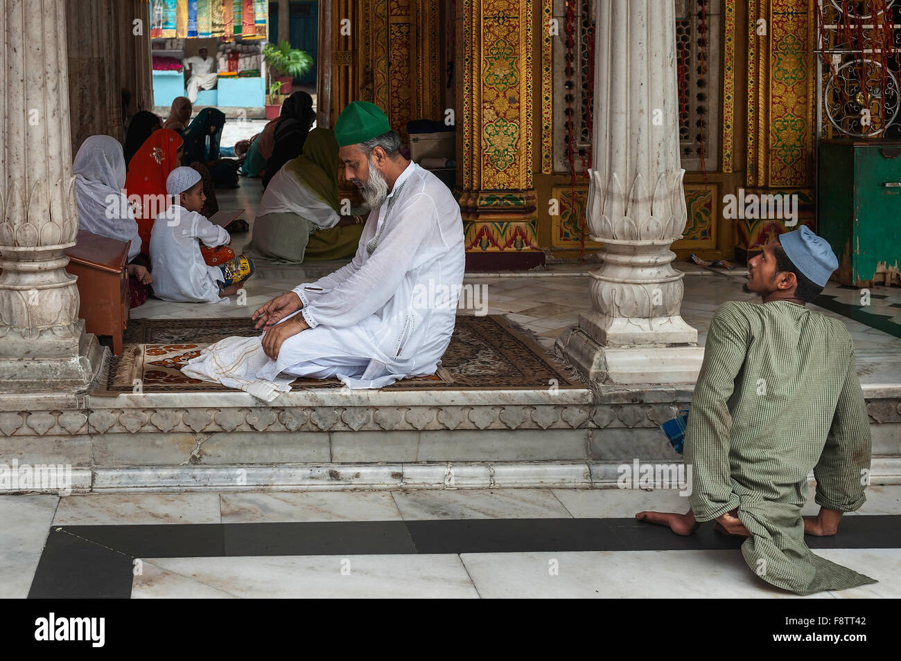 Disabled beggar waits patiently for a potential patron to finish his prayers at the beautiful mosque, Nizamuddin, Delhi, India. Stock Photo