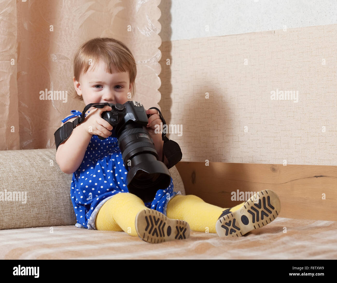 Happy baby girl takes photo with camera in home Stock Photo - Alamy