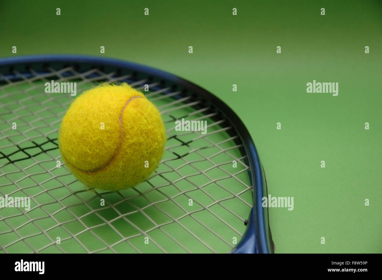 Tennis ball and racket on green background Stock Photo - Alamy