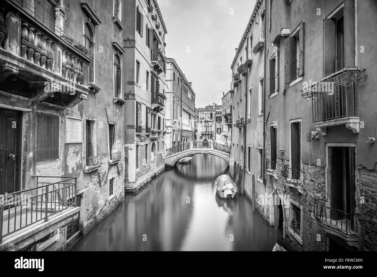 B&W narrow canal with silky water in Venice, Italy Stock Photo