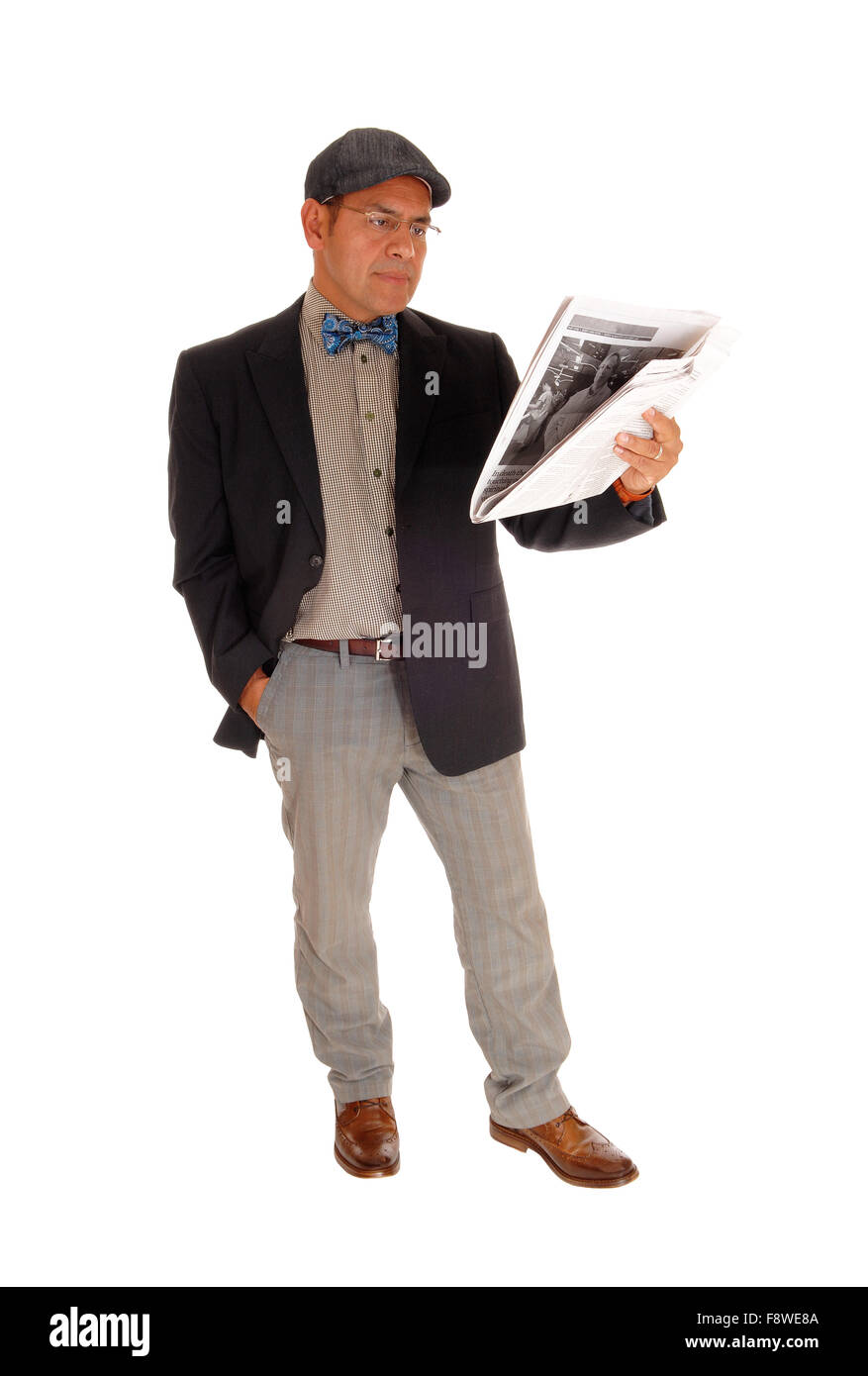 A Hispanic man in a jacket and bow tie standing isolated for white background reading his newspaper. Stock Photo