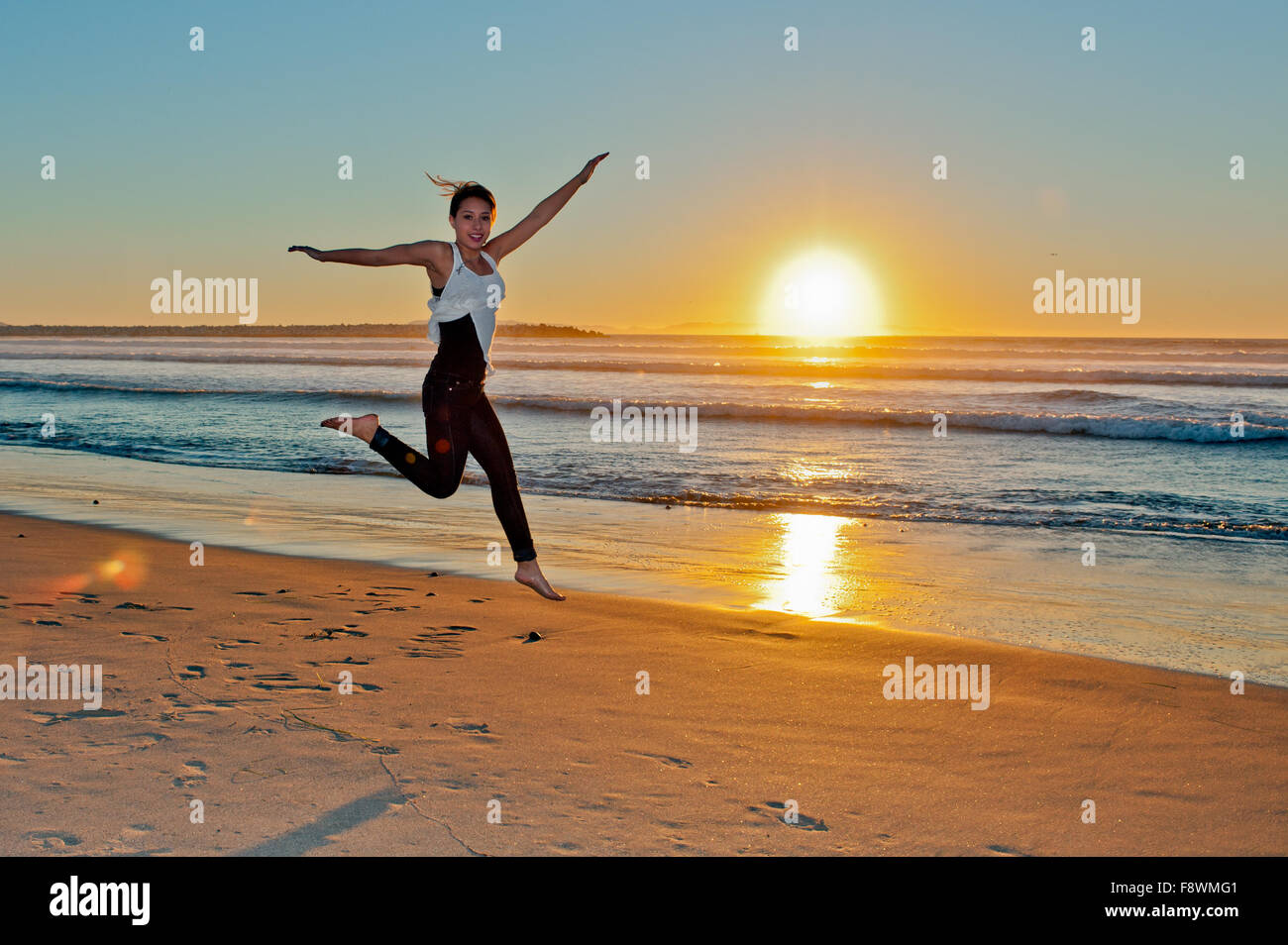 Beautiful Mexican teen skipping the beach at sunset Stock Photo