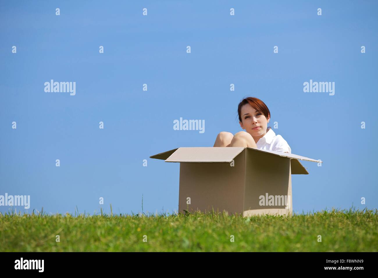 Young woman sitting in cardboard box at park Stock Photo - Alamy