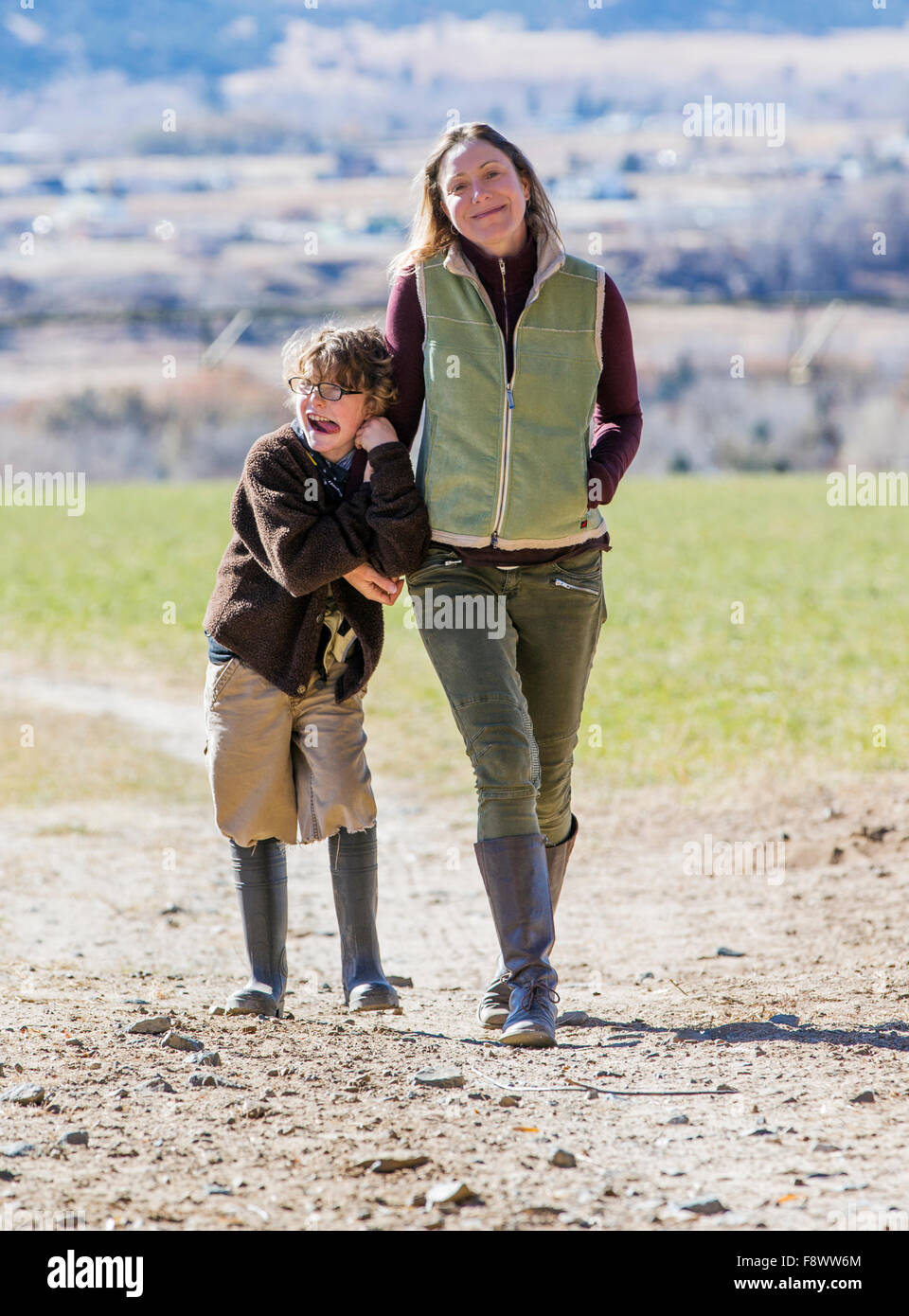 Attractive mother and young son walking along dirt path on ranch Stock Photo