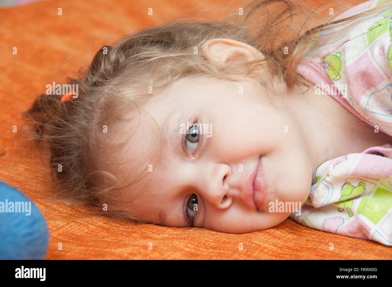 Cheerful three year old girl lying on the bed and looked into the frame Stock Photo Alamy