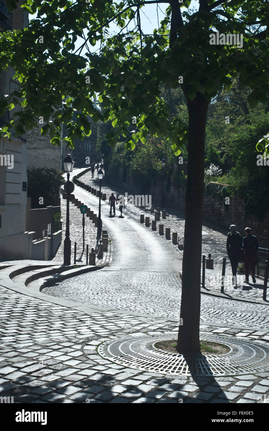 Montmartre district of Paris cobblestone street scene with two people walking up cobble stone sidewalk. Stock Photo