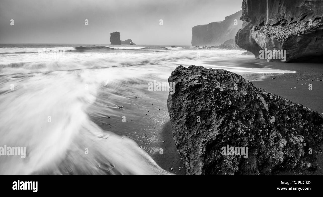 Outside of Vik. Water washing up onto black sand beach. Stock Photo