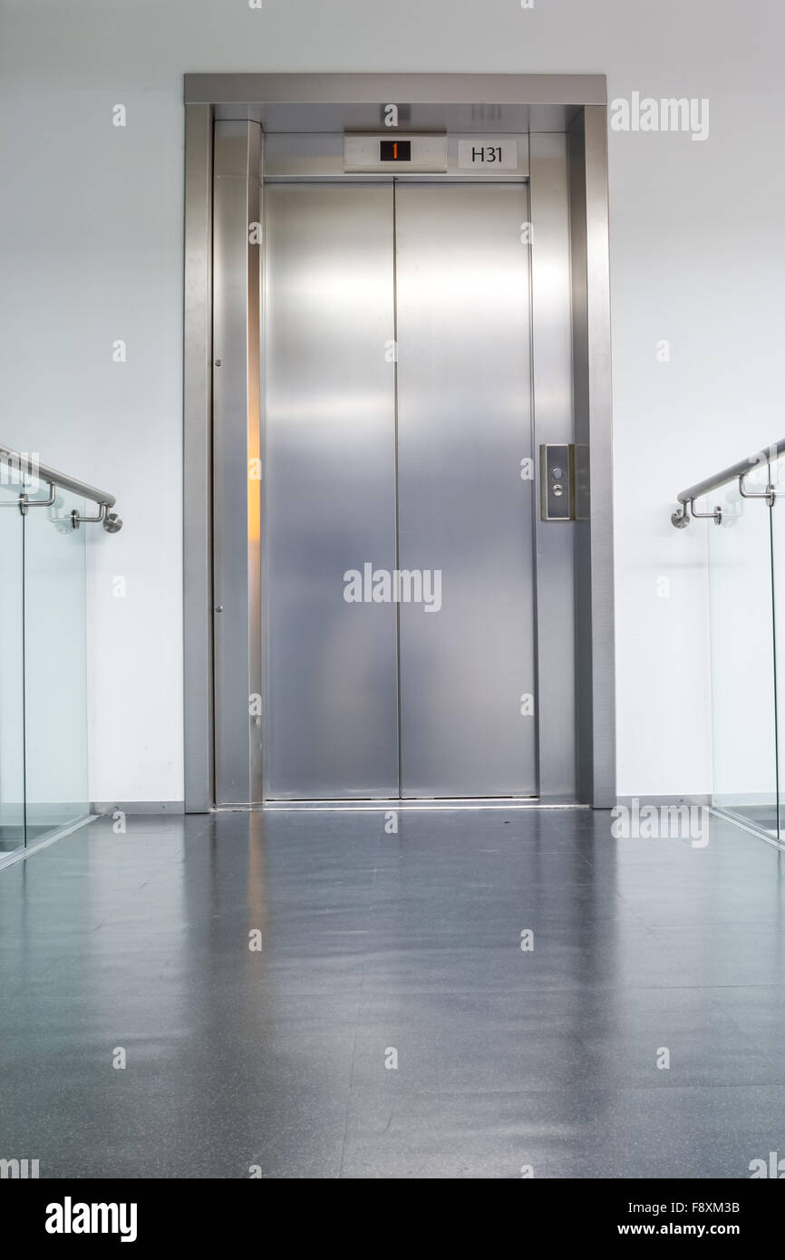 an closed elevator on the first floor of an long corridor Stock Photo