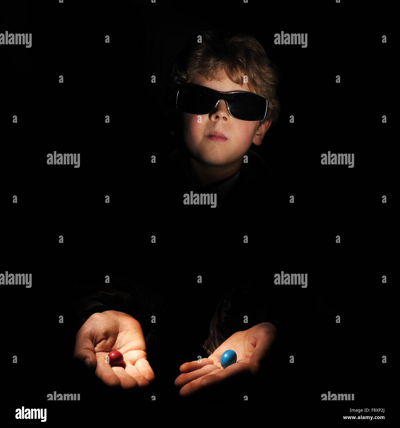 boy offering a blue and red pill as if Morpheus in Matrix Stock Photo