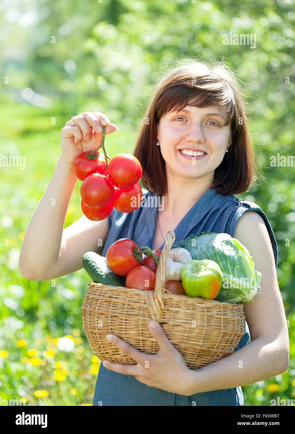 Happy young woman with basket of harvested vegetables in garden Stock ...