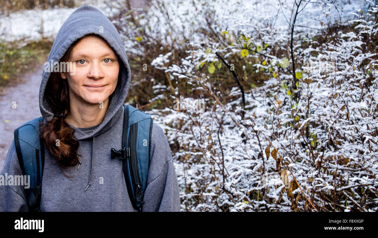Woman in a hoodie on a hike with snow on the ground Stock Photo
