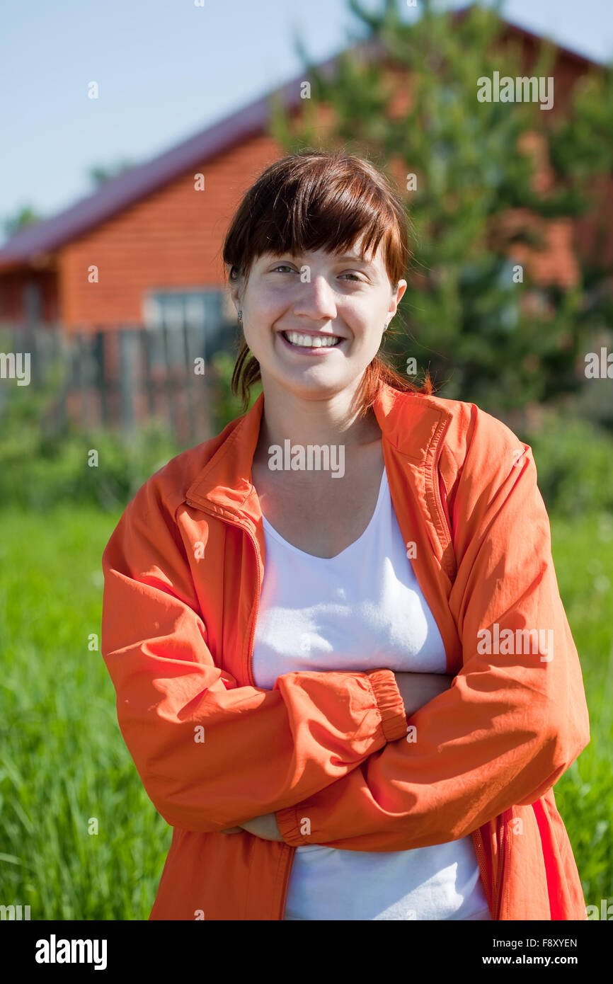 Happy young woman in front of new home Stock Photo - Alamy
