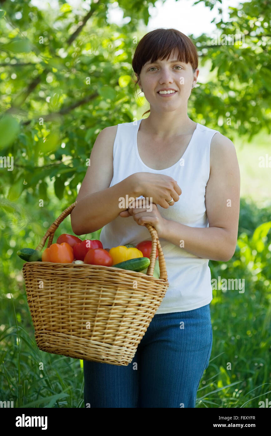 Happy young woman with basket of harvested vegetables in garden Stock ...