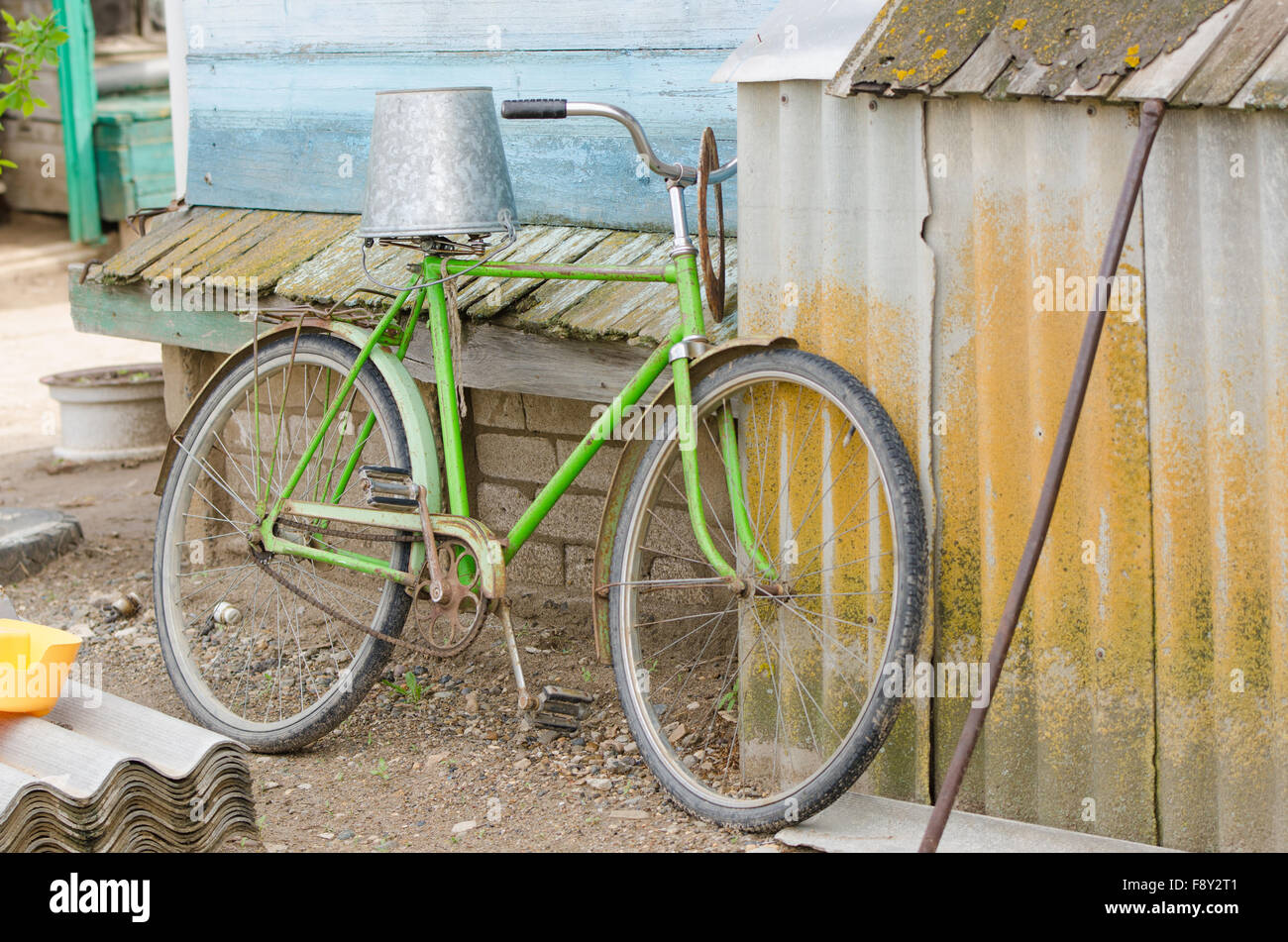 old bicycle with a bucket upside down on the saddle is at the wooden house Stock Photo