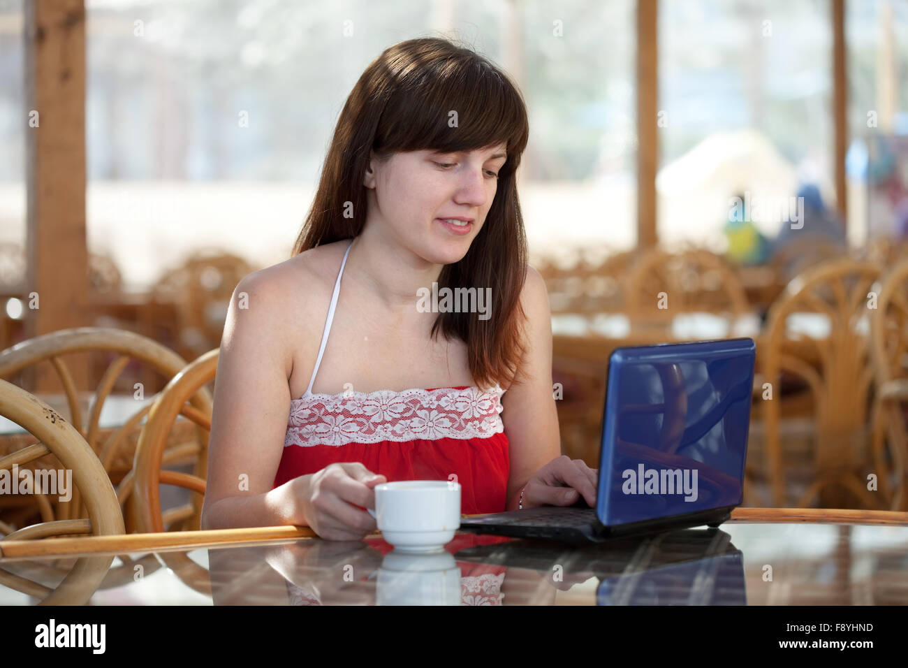 Young woman using laptop at resort cafe Stock Photo - Alamy