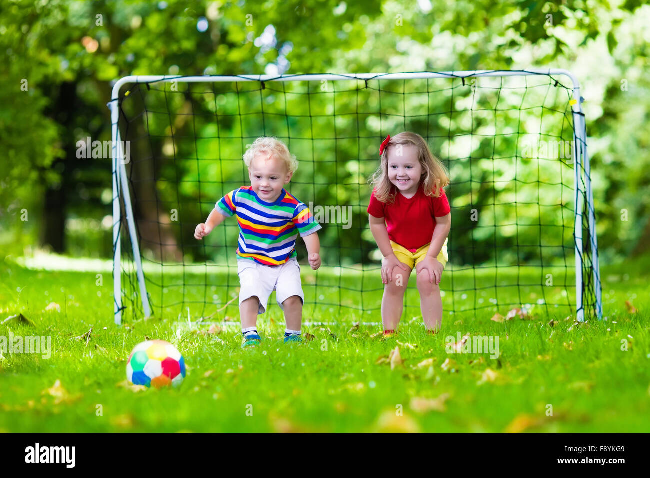 Two happy children playing European football outdoors in school yard ...