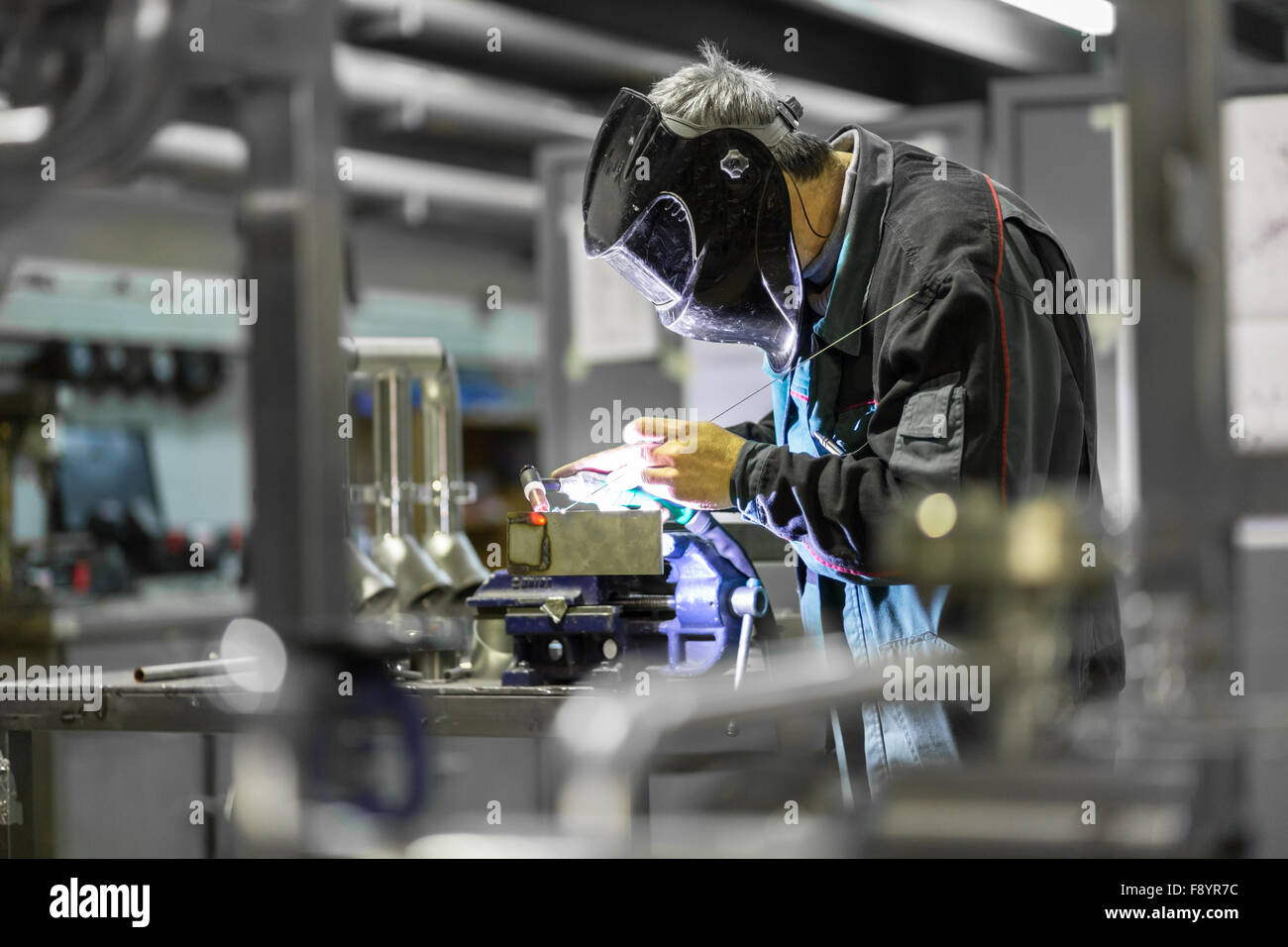 Industrial worker welding in metal factory. Stock Photo