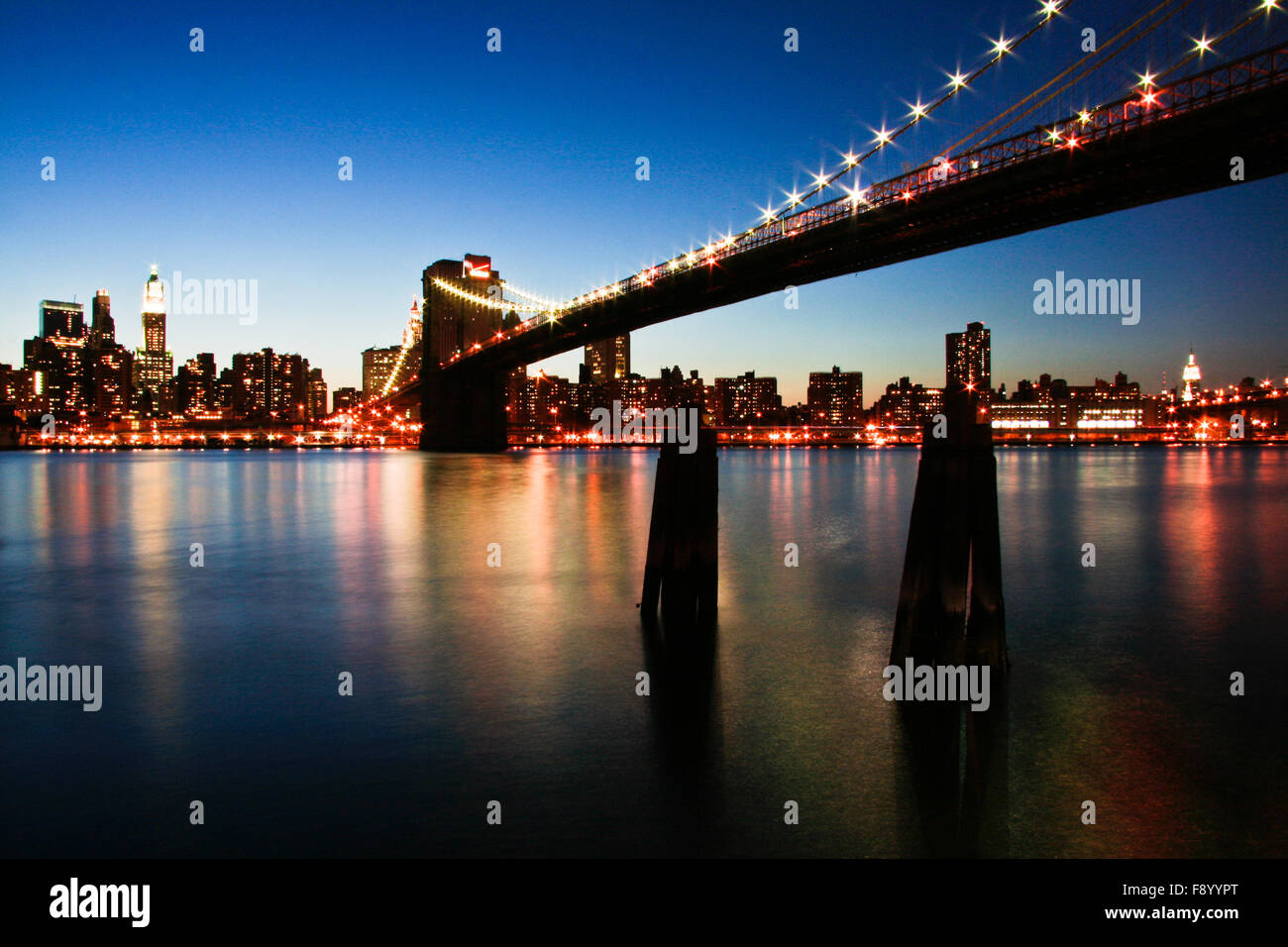 New York City Manhattan skyline panorama with Brooklyn Bridge and office skyscrapers building in at dusk illuminated with lights Stock Photo