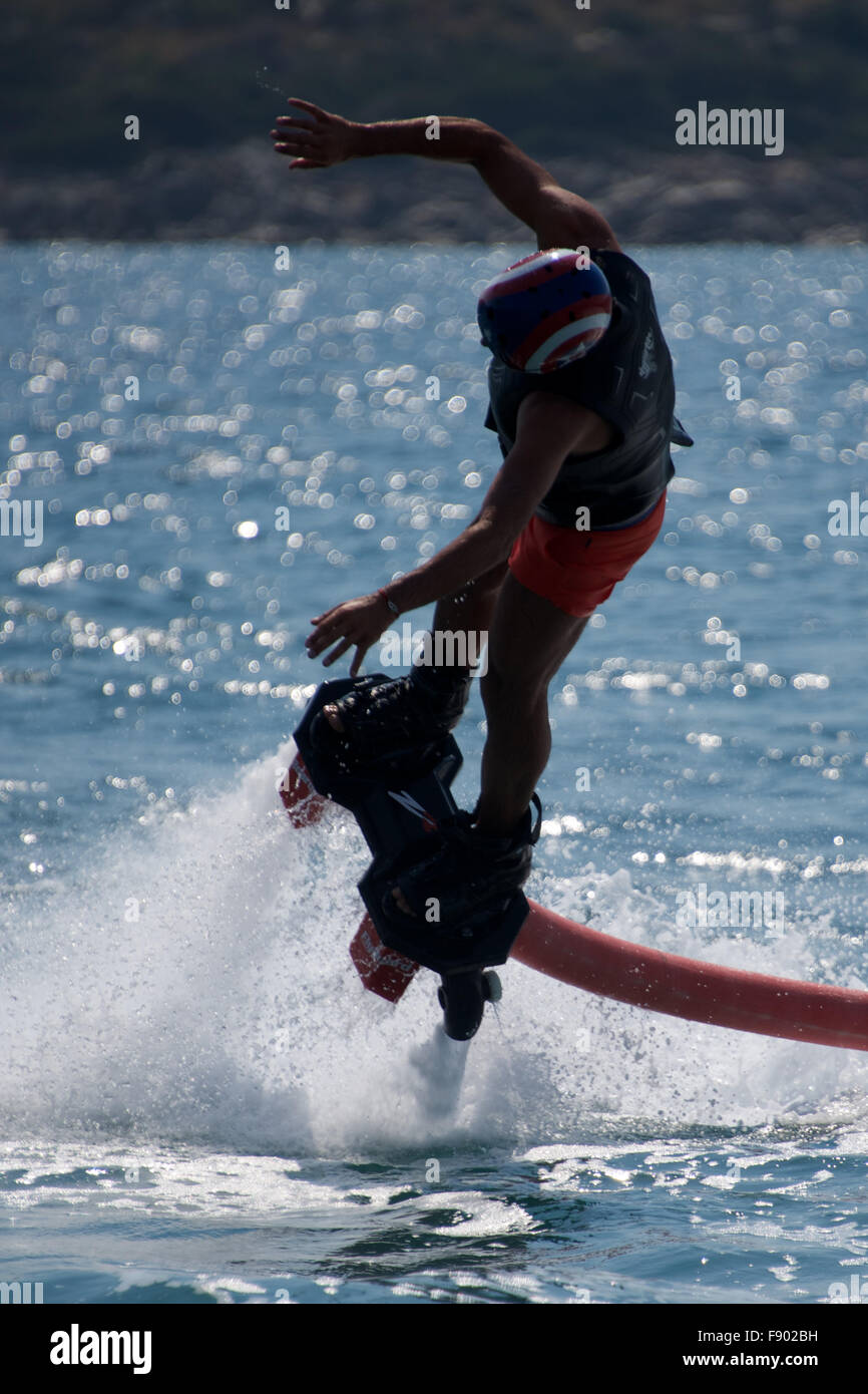 Flyboarder in helmet diving into backlit waves Stock Photo