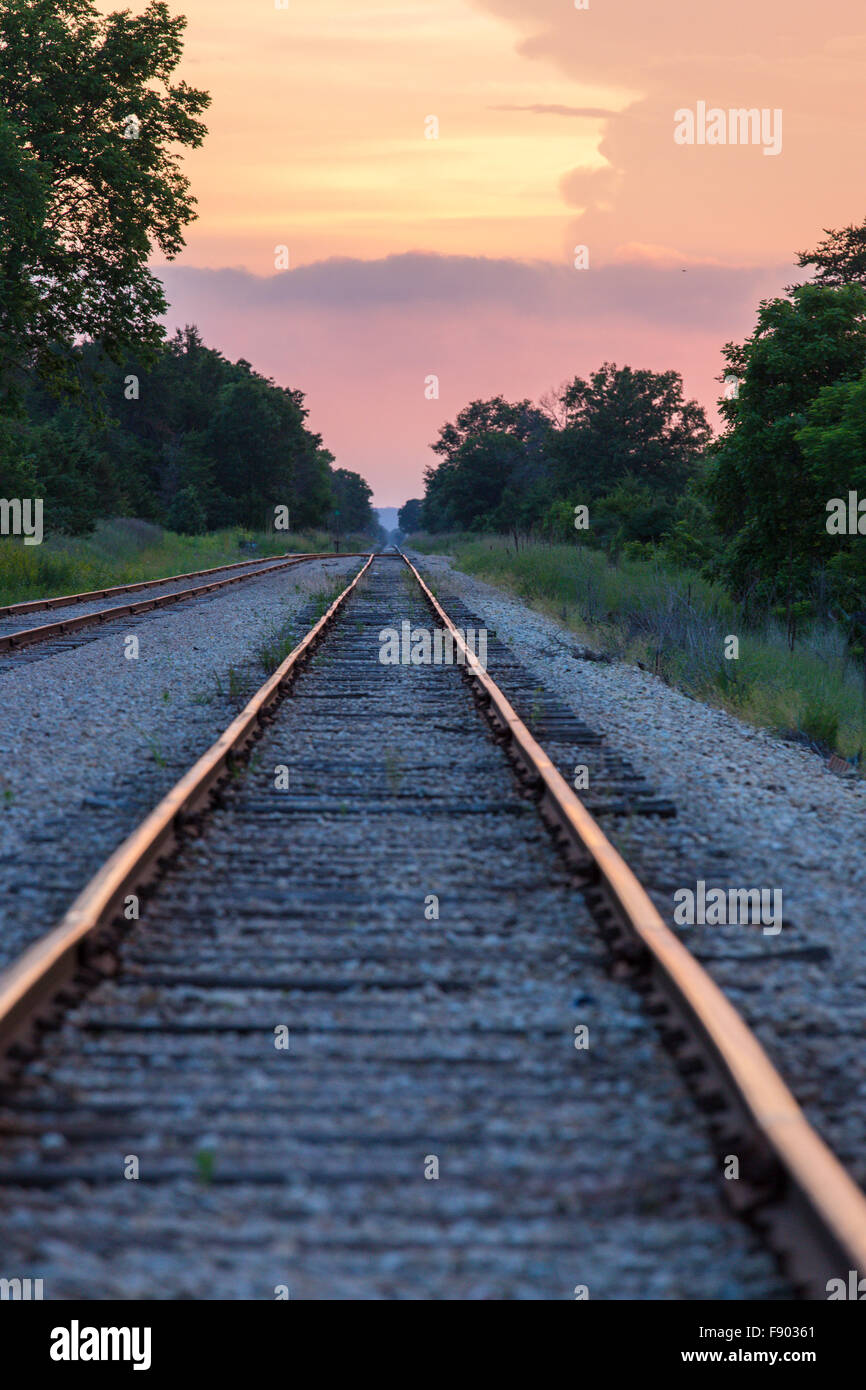 Long straight railroad tracks running into the distance at sunset with