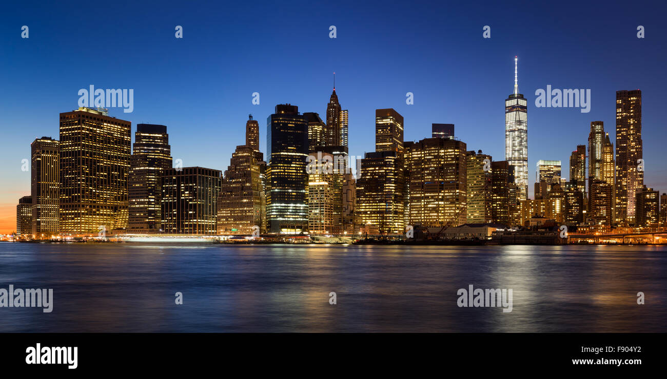New York City skyline of Lower Manhattan Financial District at twilight with  illuminated skyscrapers rising above East River Stock Photo