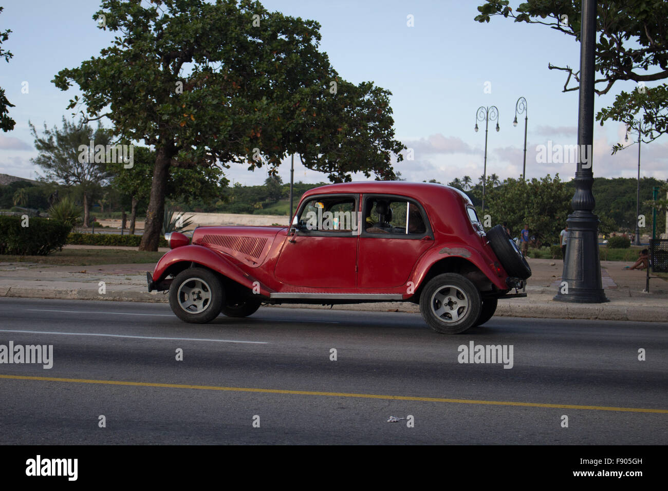 People are driving an old red car in Cuba. They are in Habana Stock Photo
