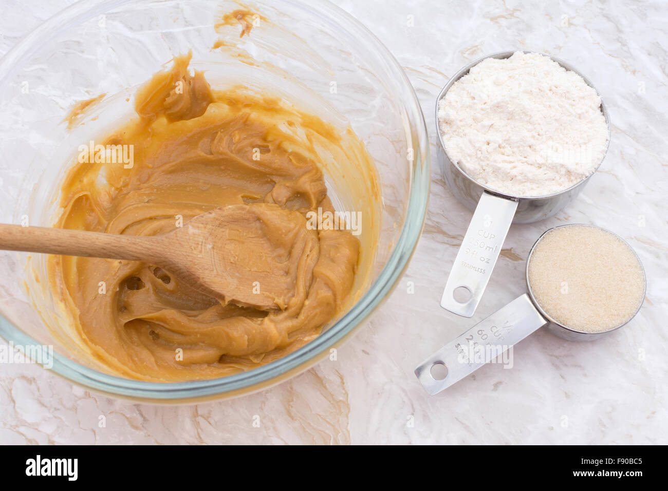 Measuring cups of flour and sugar with a peanut butter mixture in