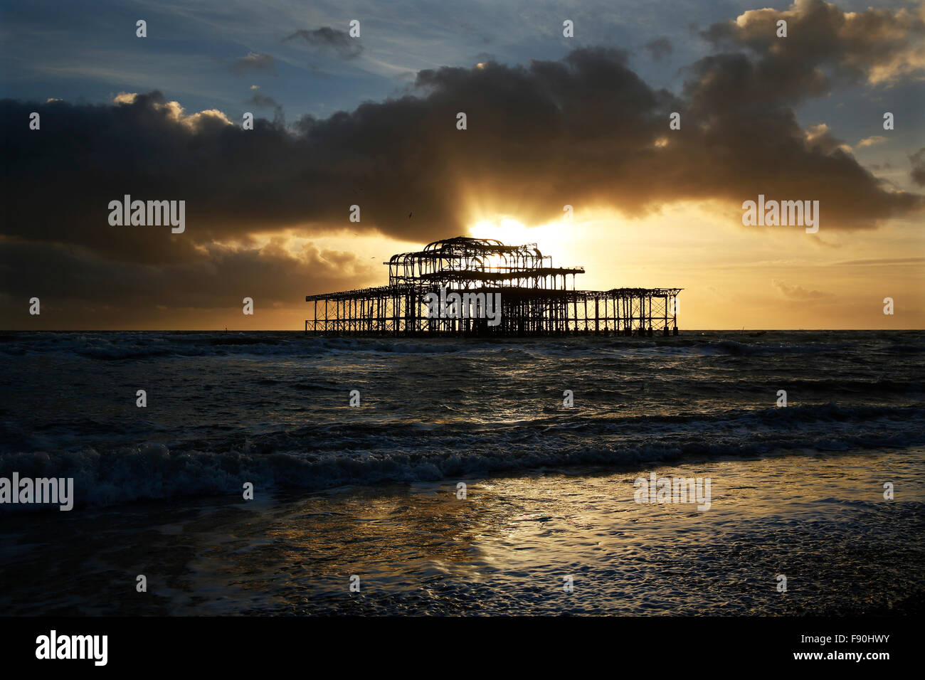 Afternoon sun shines through stormy sky behind the West Pier at Hove near Brighton, UK Stock Photo