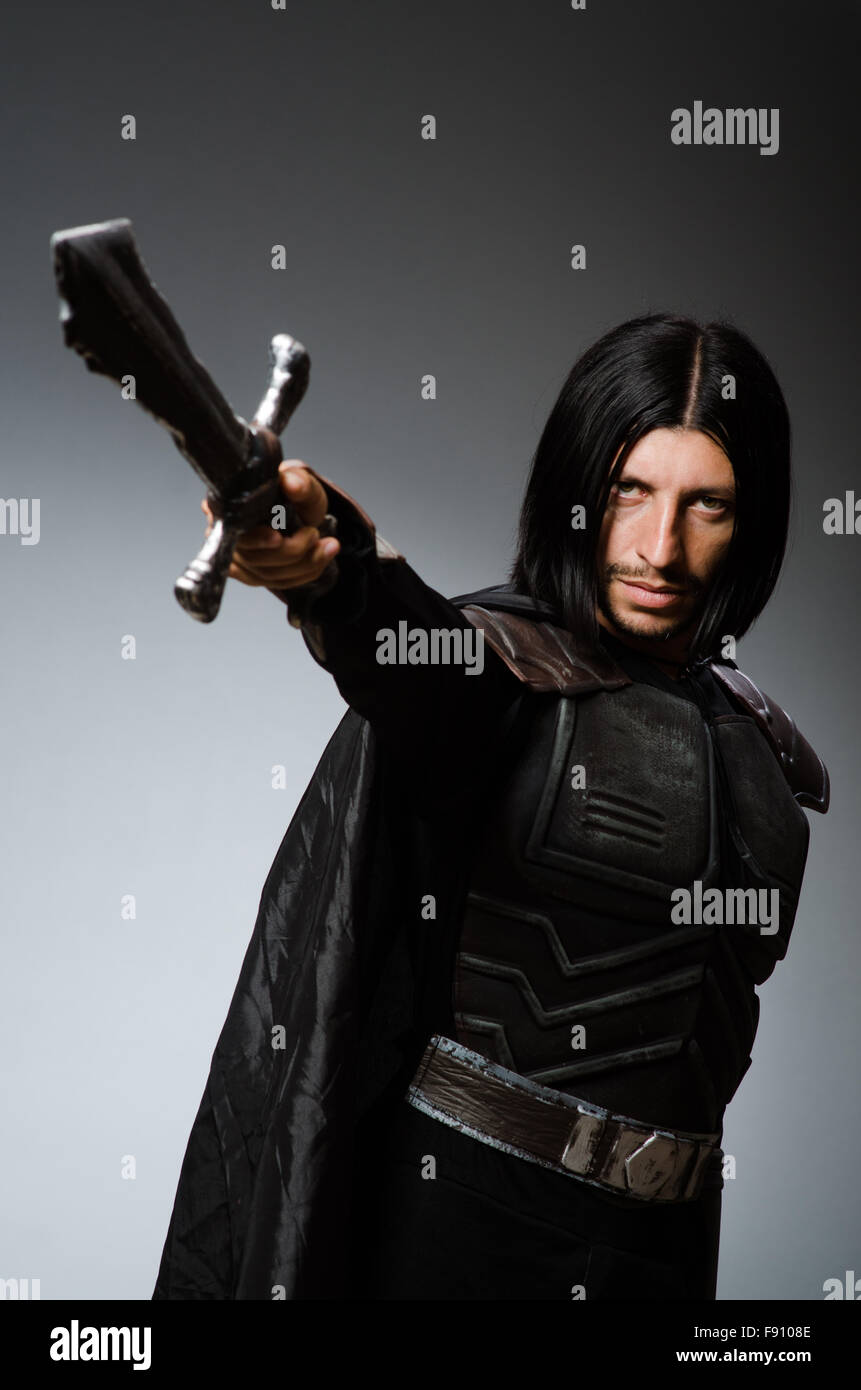 Angry knight with sword against dark background Stock Photo - Alamy
