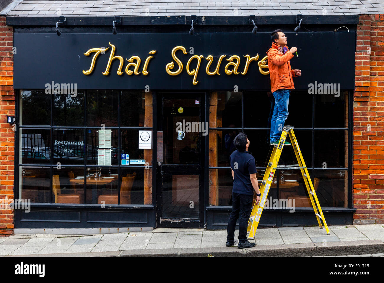 A Man Working On The Outside Of A Thai Restaurant In Windsor, Berkshire, UK Stock Photo