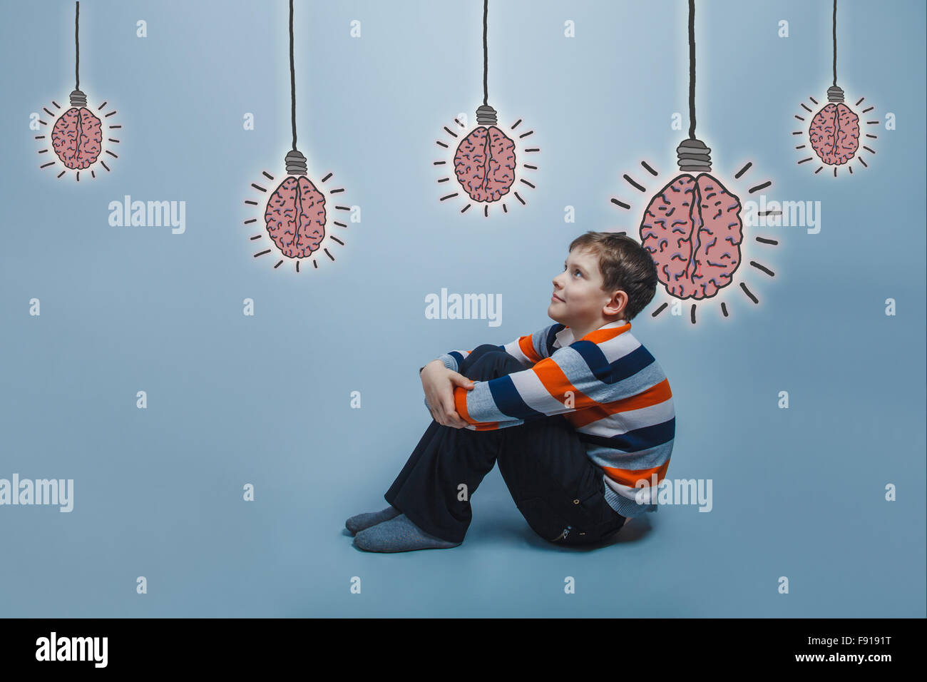 adolescent boy sitting on the floor hugging his knees smiling lo Stock ...