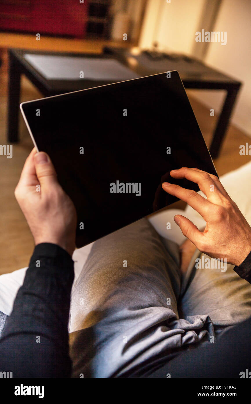 Modern middle-aged man enjoying a quiet moment comfortably at his home with a tablet on a blurred background Stock Photo