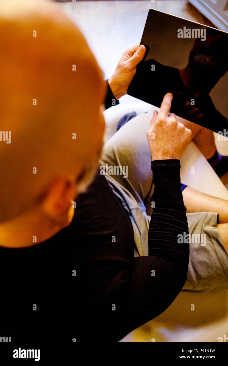 Modern middle-aged man enjoying a quiet moment comfortably at his home with a tablet on a blurred background Stock Photo