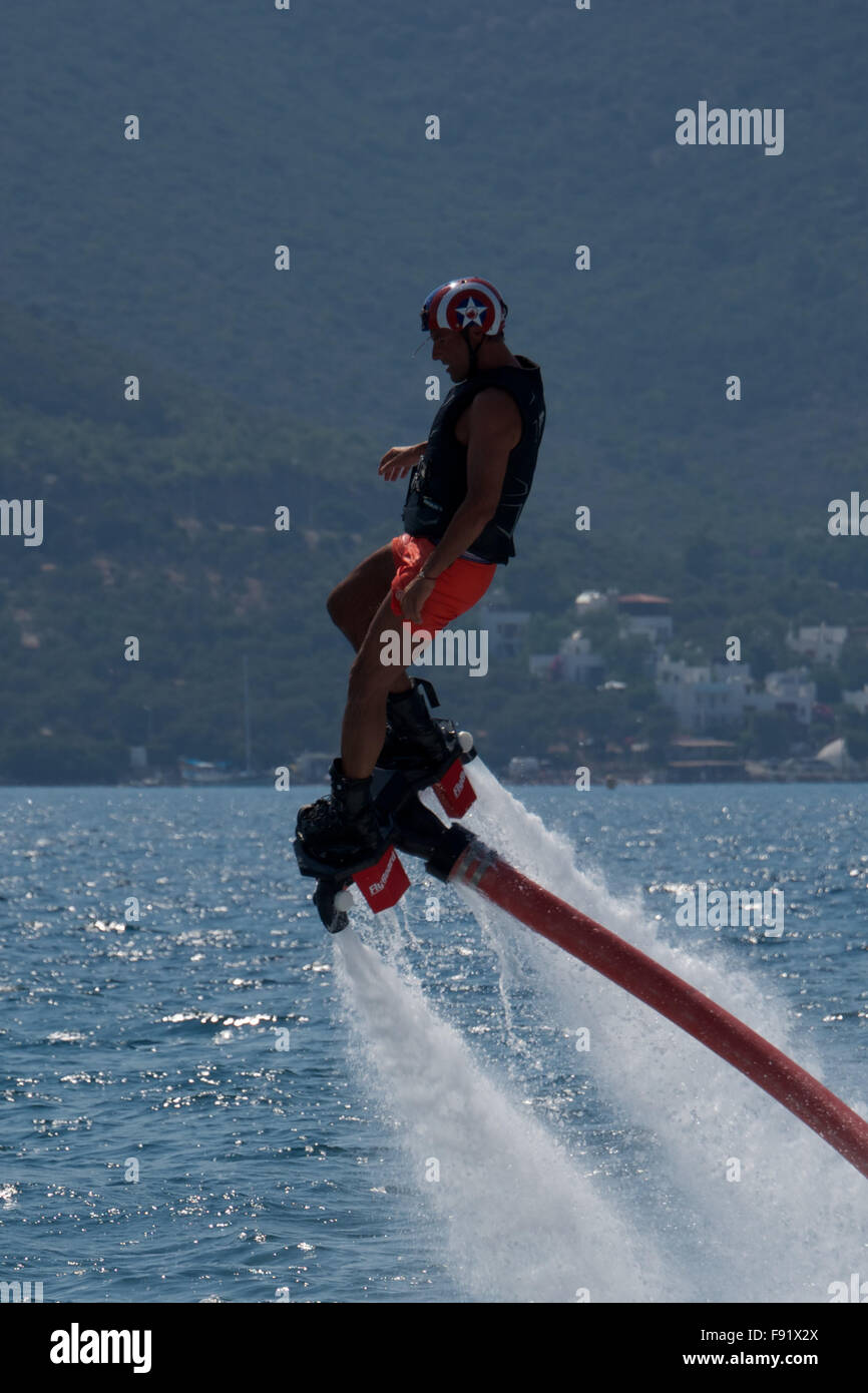 Flyboarder leaning over backwards amid backlit waves Stock Photo