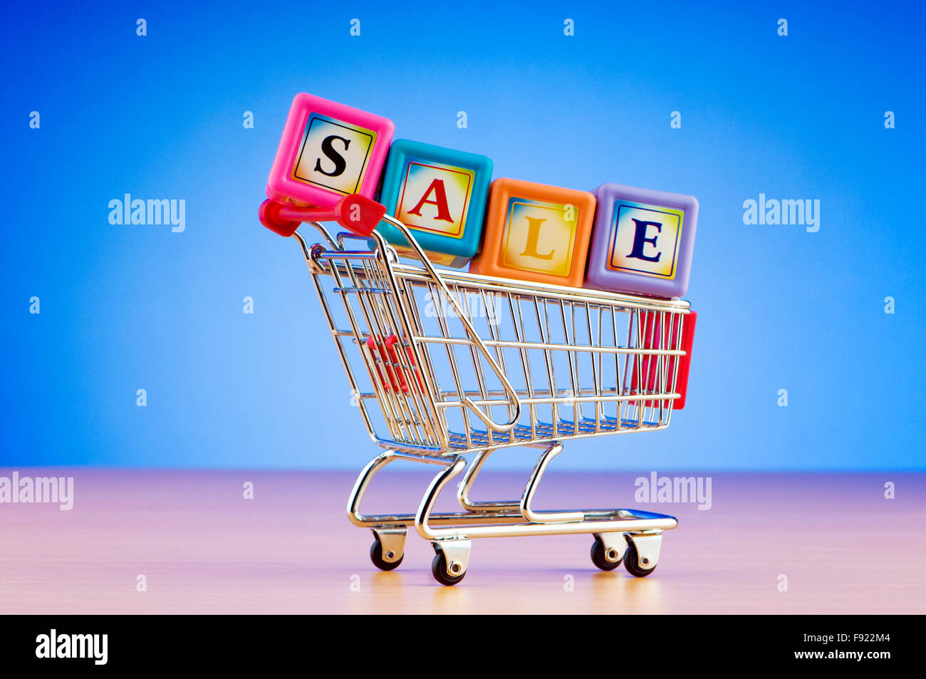 Mini shopping cart against gradient background Stock Photo
