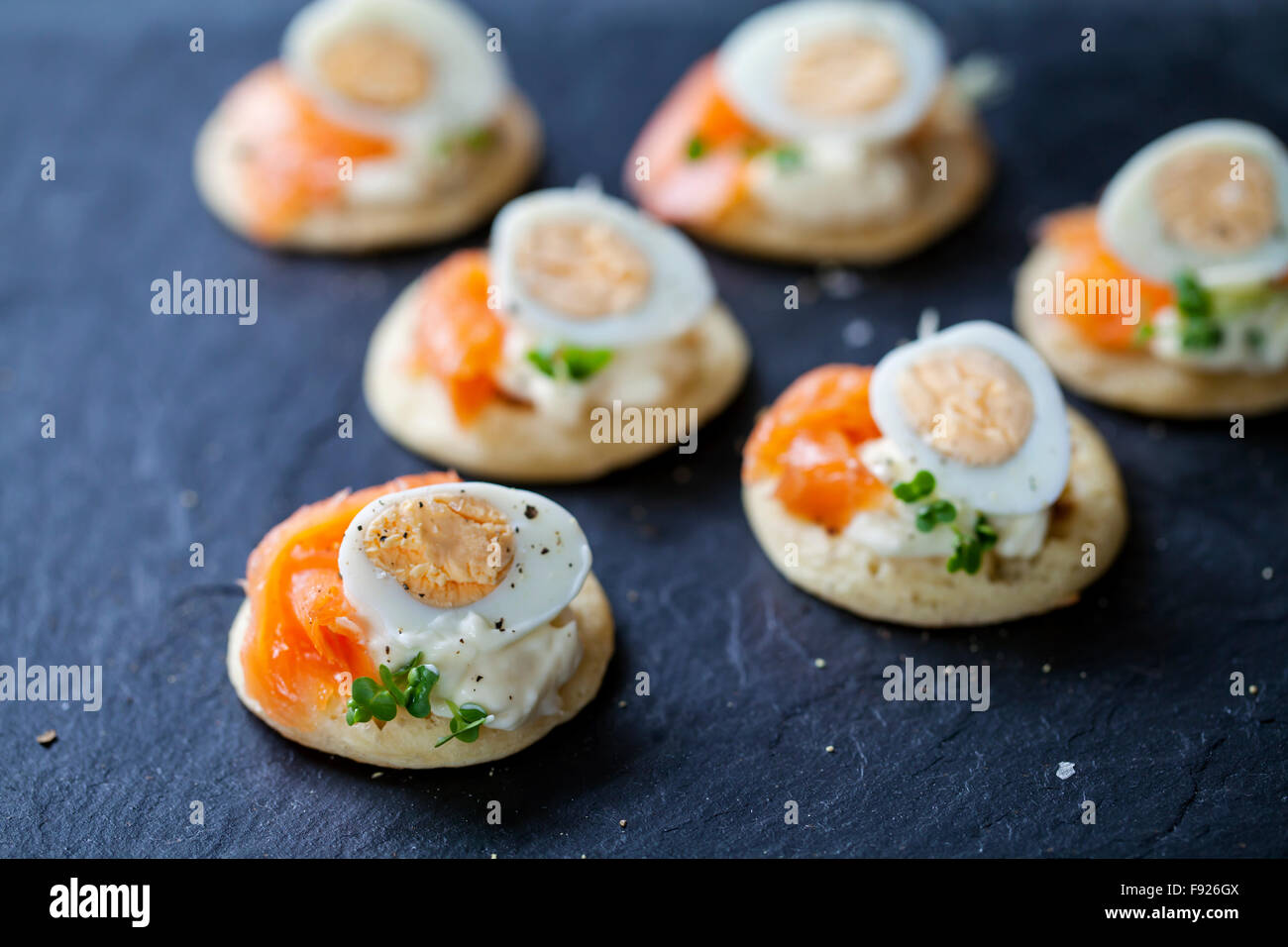 Party food, blinis with salmon, quail egg and caviar Stock Photo