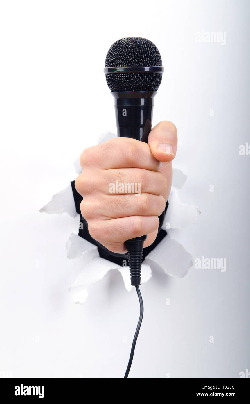 Hand holding microphone through hole in paper Stock Photo - Alamy