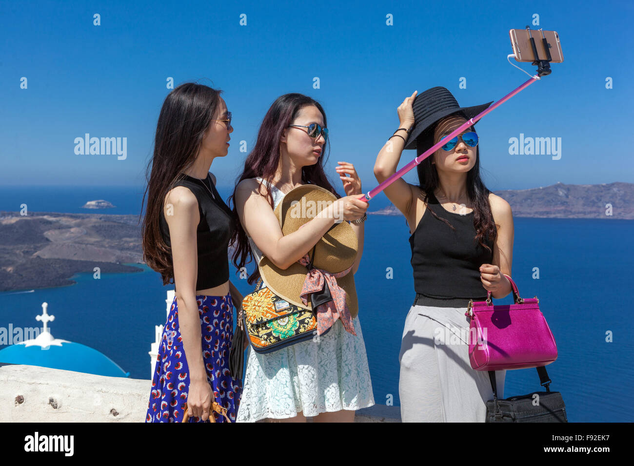 Santorini selfie, Three Women People Young Asian tourists taking a selfie on phone stick Santorini tourists Greece Stock Photo