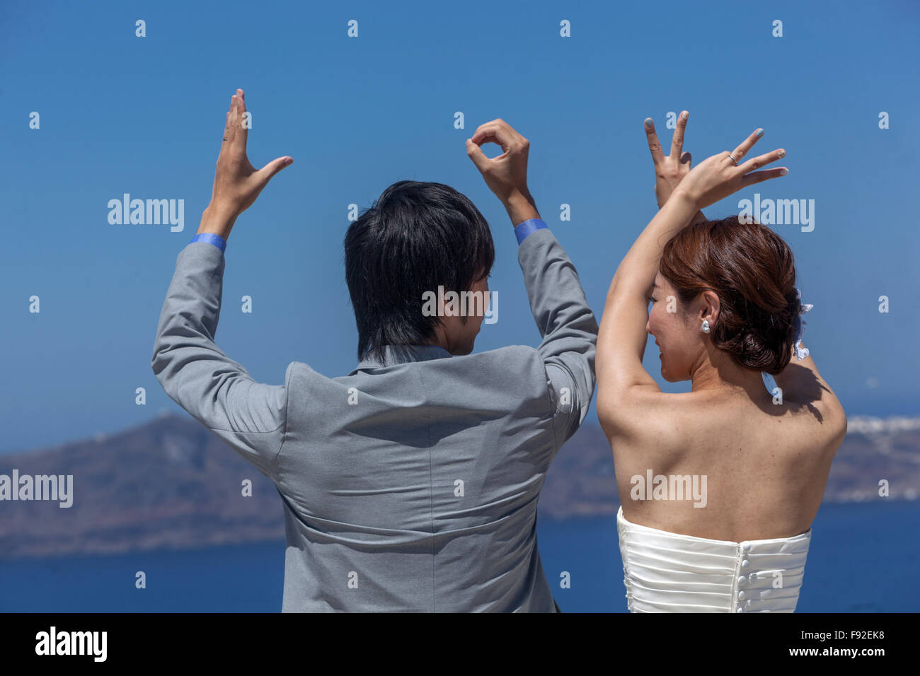 Inscription Love, Young Asian people just married, Santorini couple rear view, Greek island, Greece Stock Photo