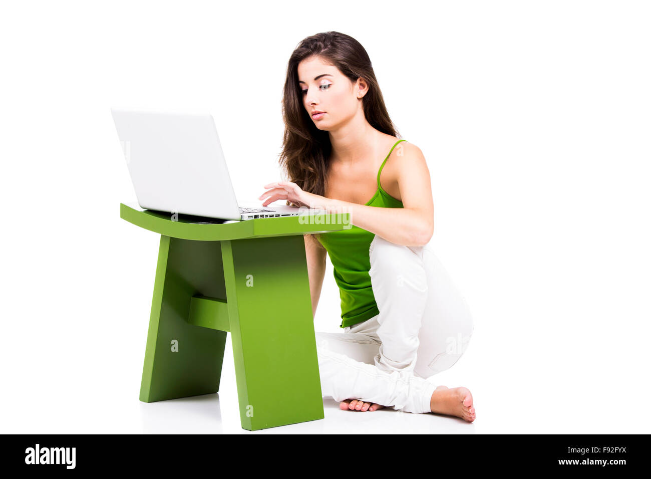 Beautiful woman sitting in the floor working with a laptop, isolated ...