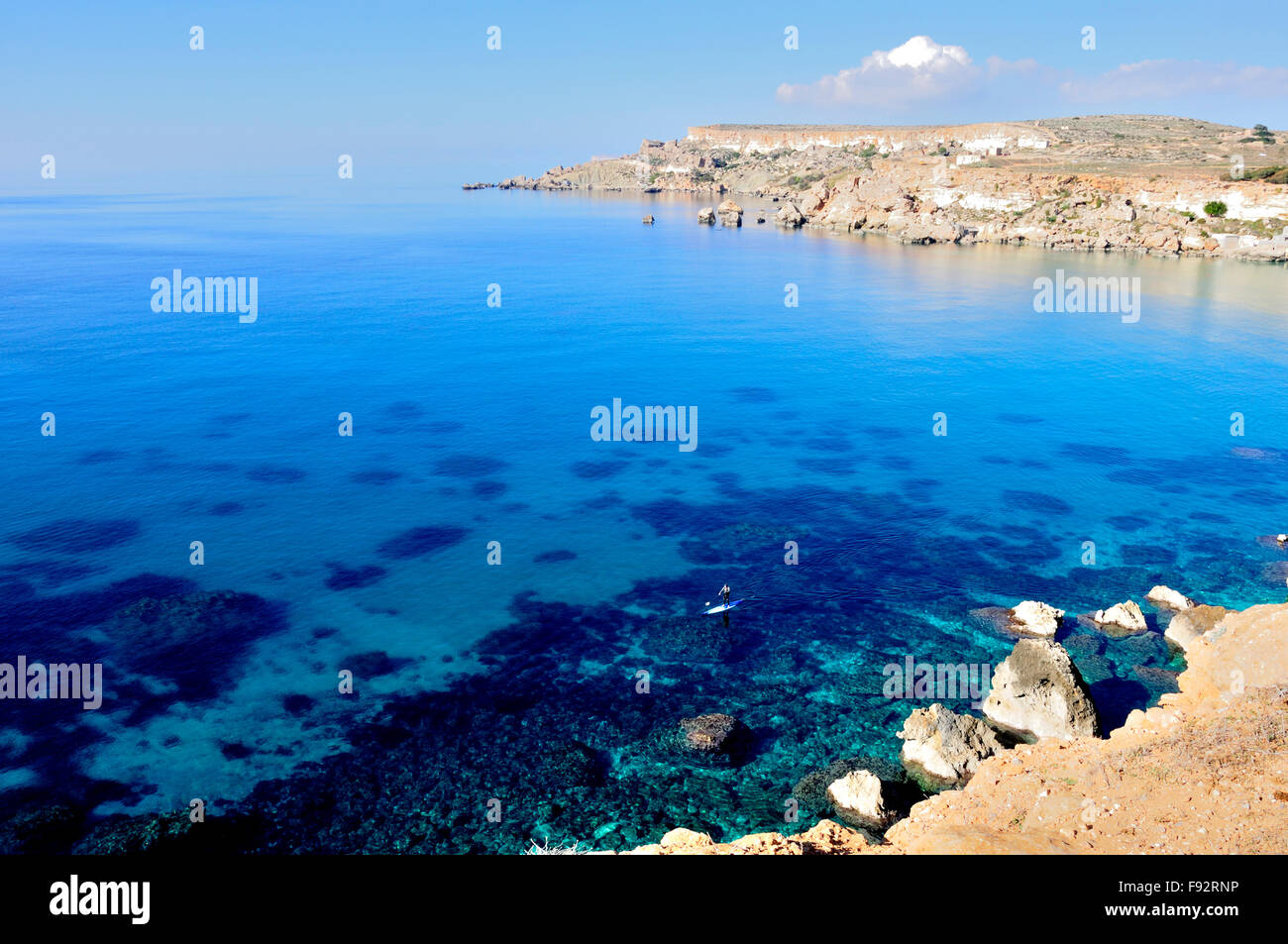 a brilliant blue sea and sky in Malta in December. Man paddle-boarding (small scale) Stock Photo