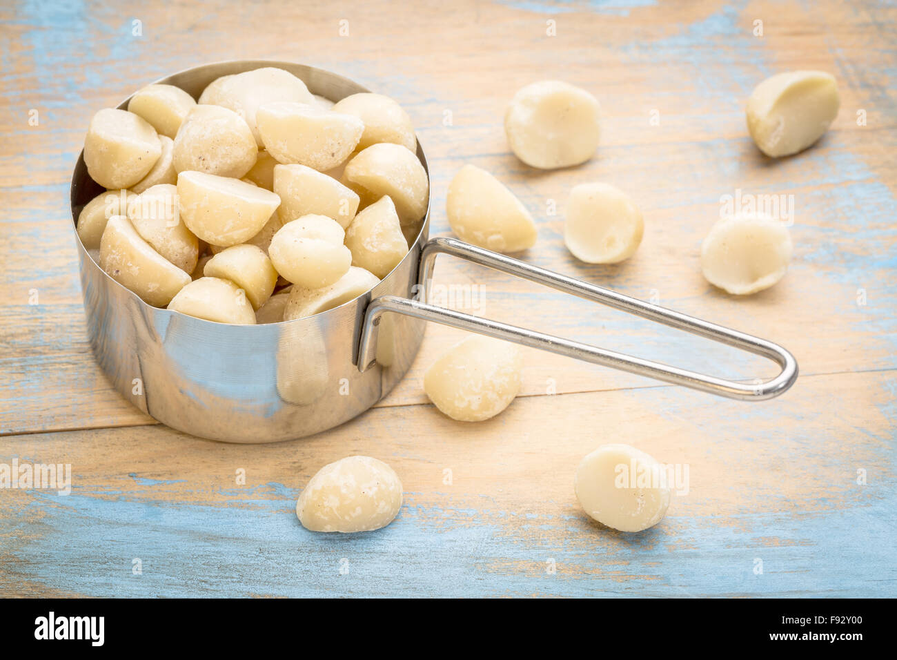 macadamia nuts in a metal measuring scoop (1/2 cup) against rustic barn