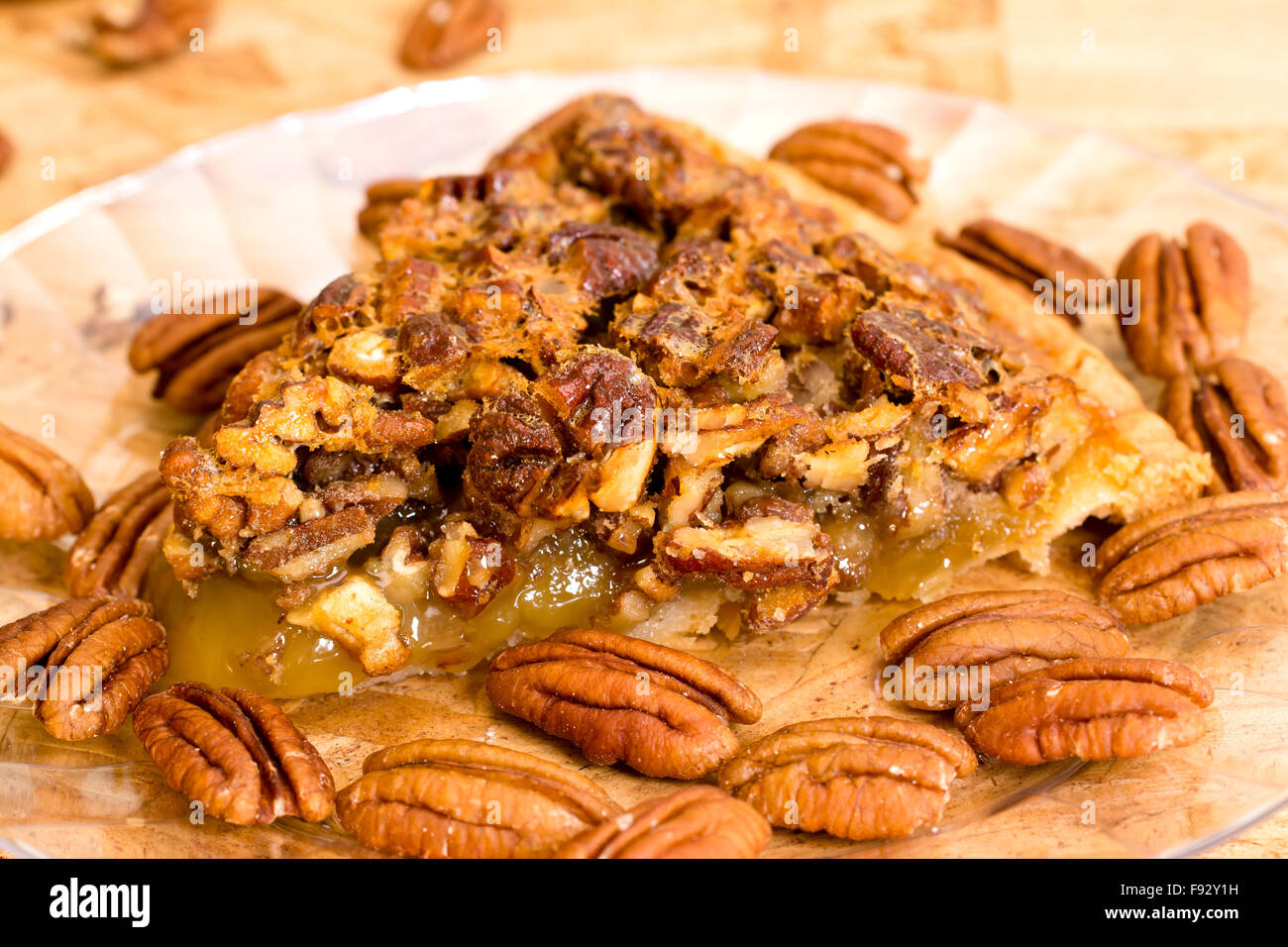 Pecan pie slice closeup with pecans on wooden background. Stock Photo