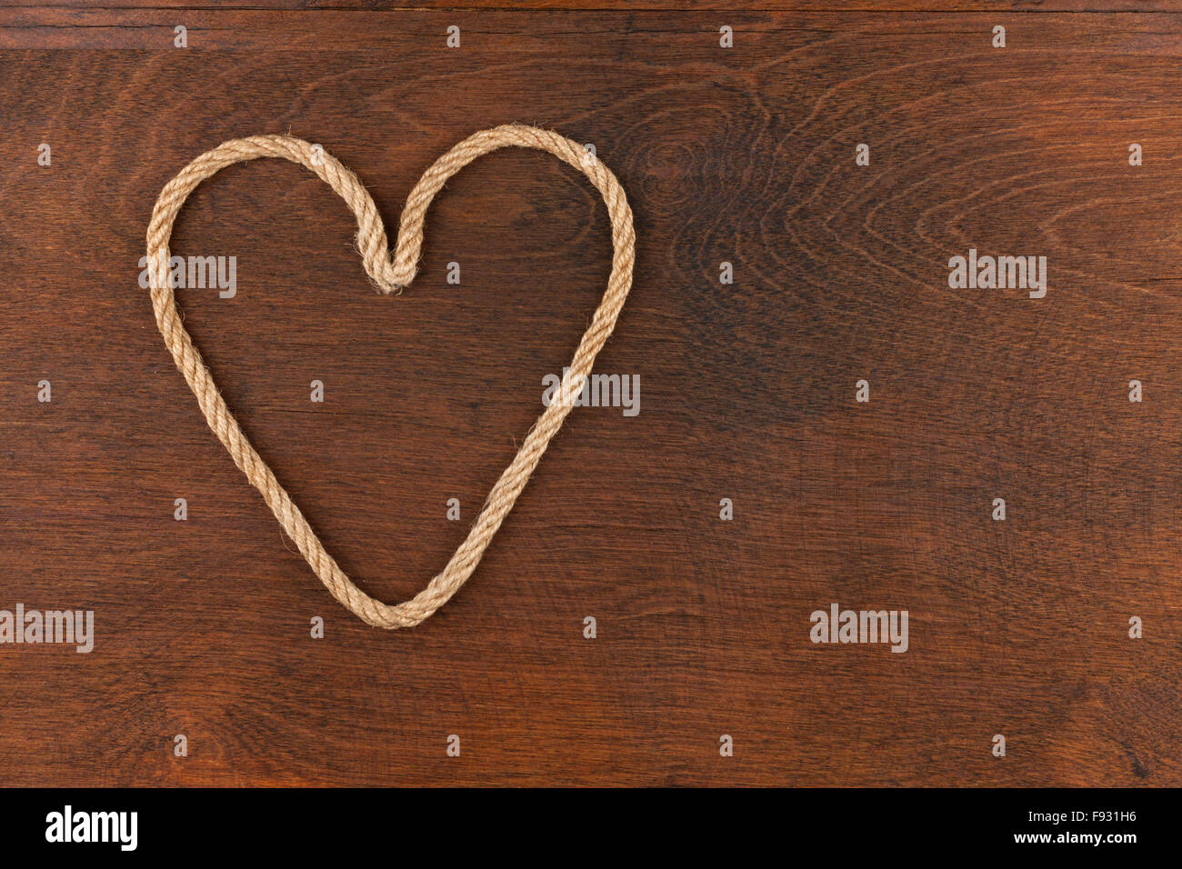 Symbolic heart made of rope lying on a wooden surface , as background Stock Photo