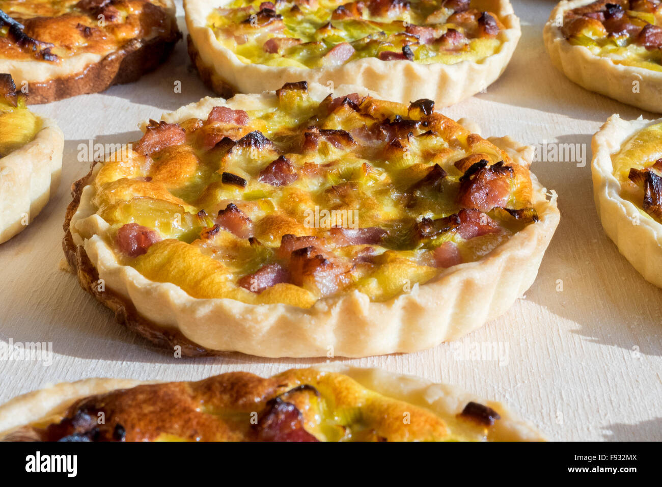 Assortment of quiche lorraine tartlets on wooden board, hand made with