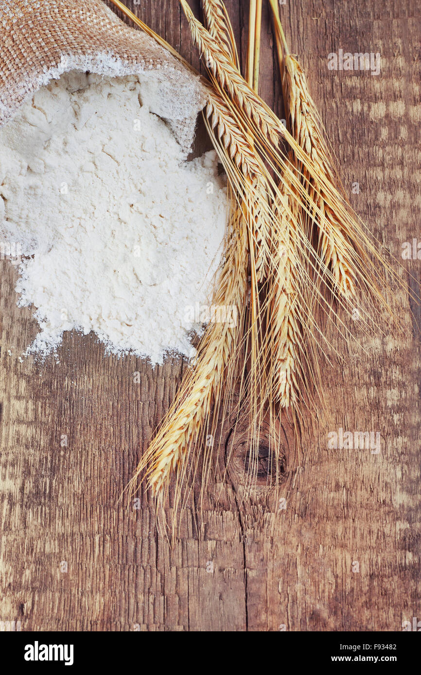 sack bag of white flour with wheat ears on wooden background Stock Photo