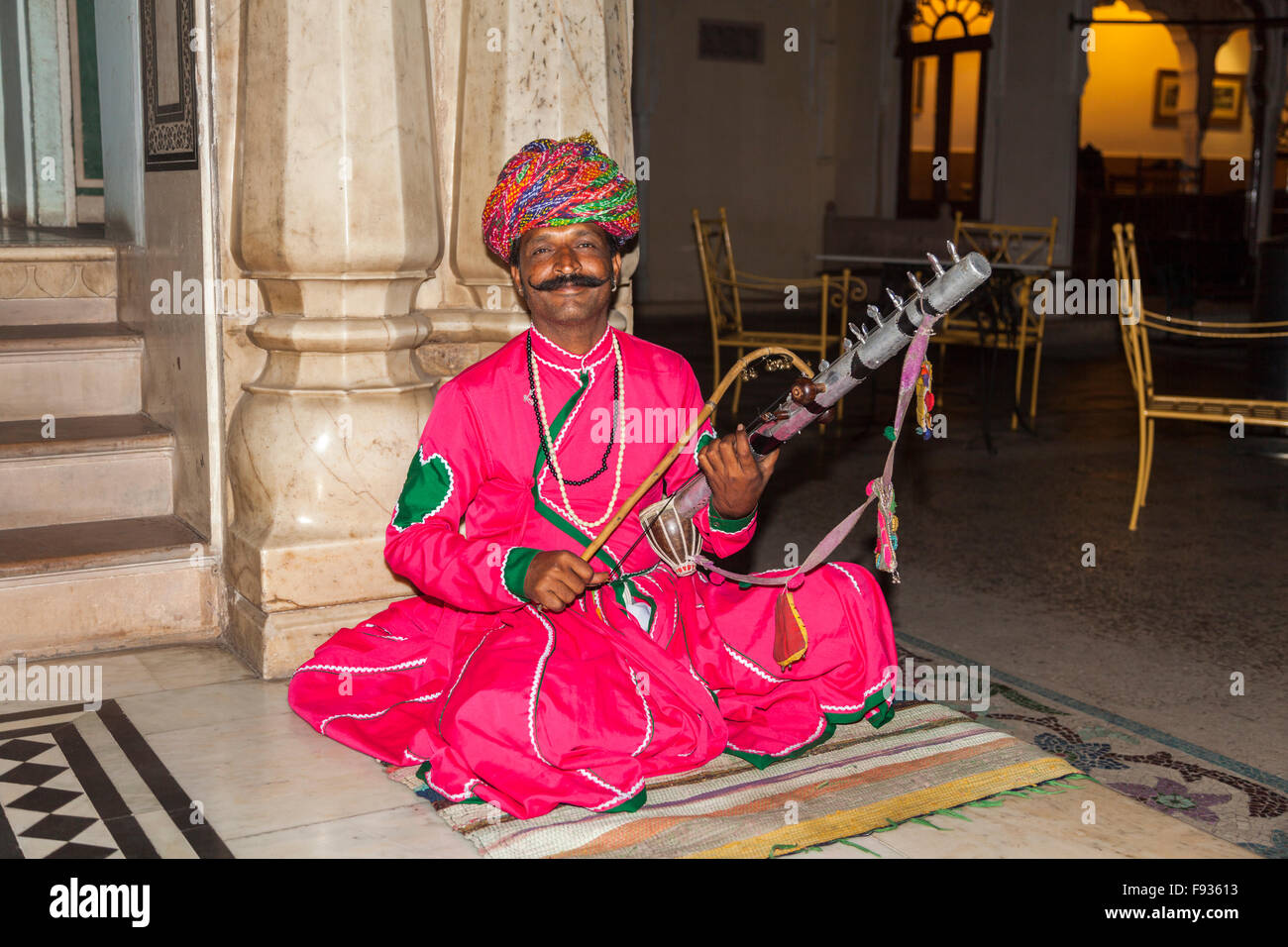 Local musician with large mustache dressed in colourful clothing and turban entertaining in a hotel in Jaipur, Rajasthan, India Stock Photo